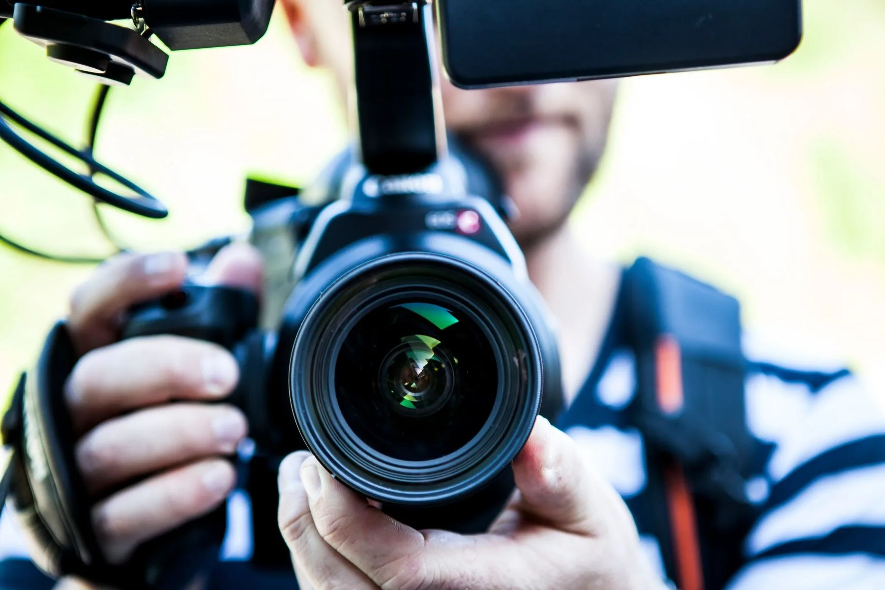 An operator holding a mirrorless camera with an external monitor attached