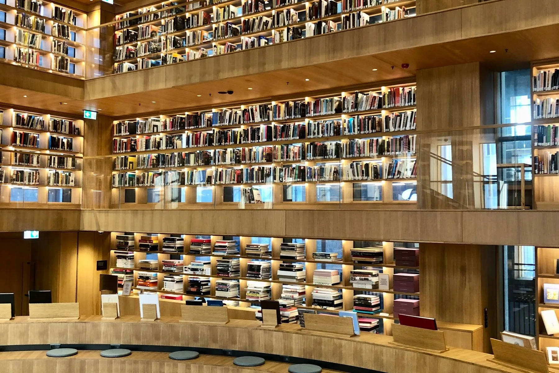 A curved modern library reading room with lit shelves and study desks