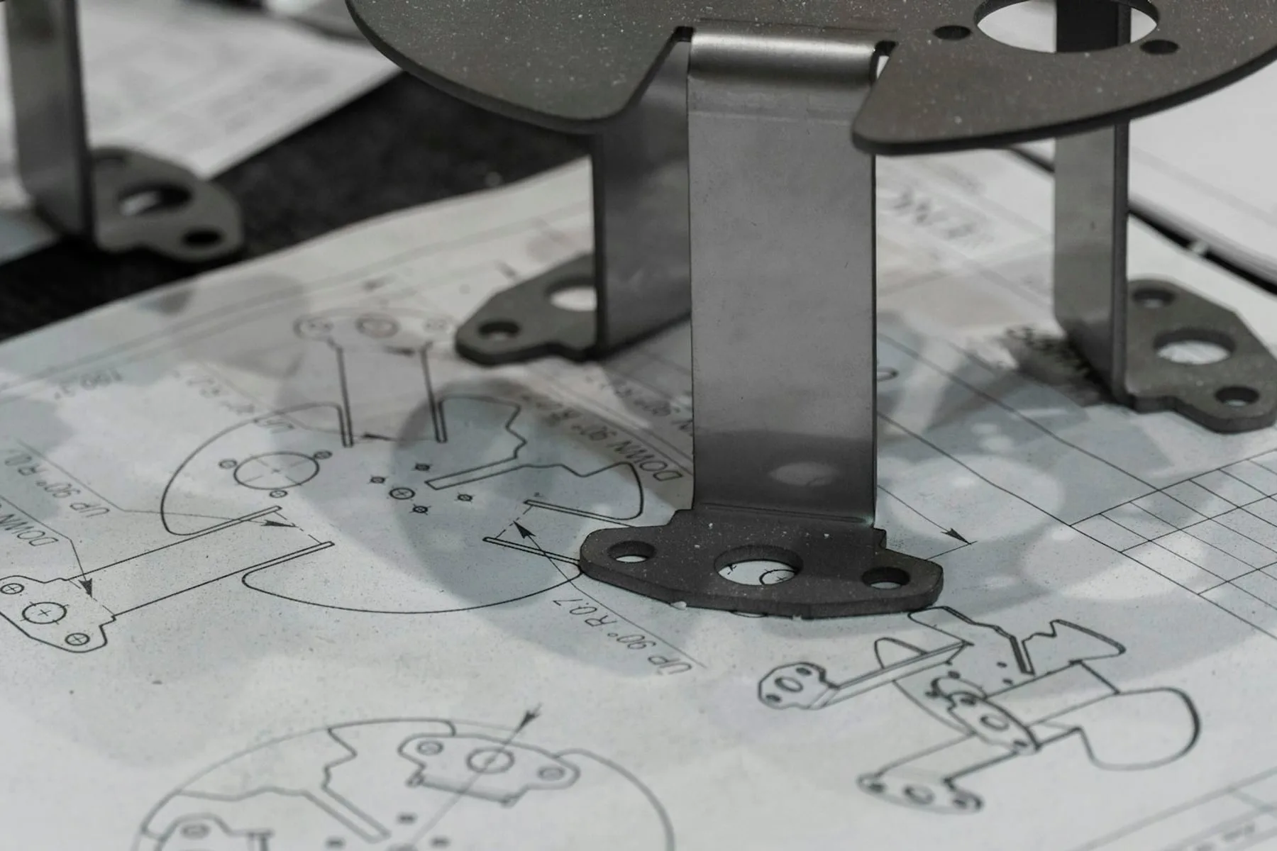Printed engineering drawings and metal parts on a wooden desk