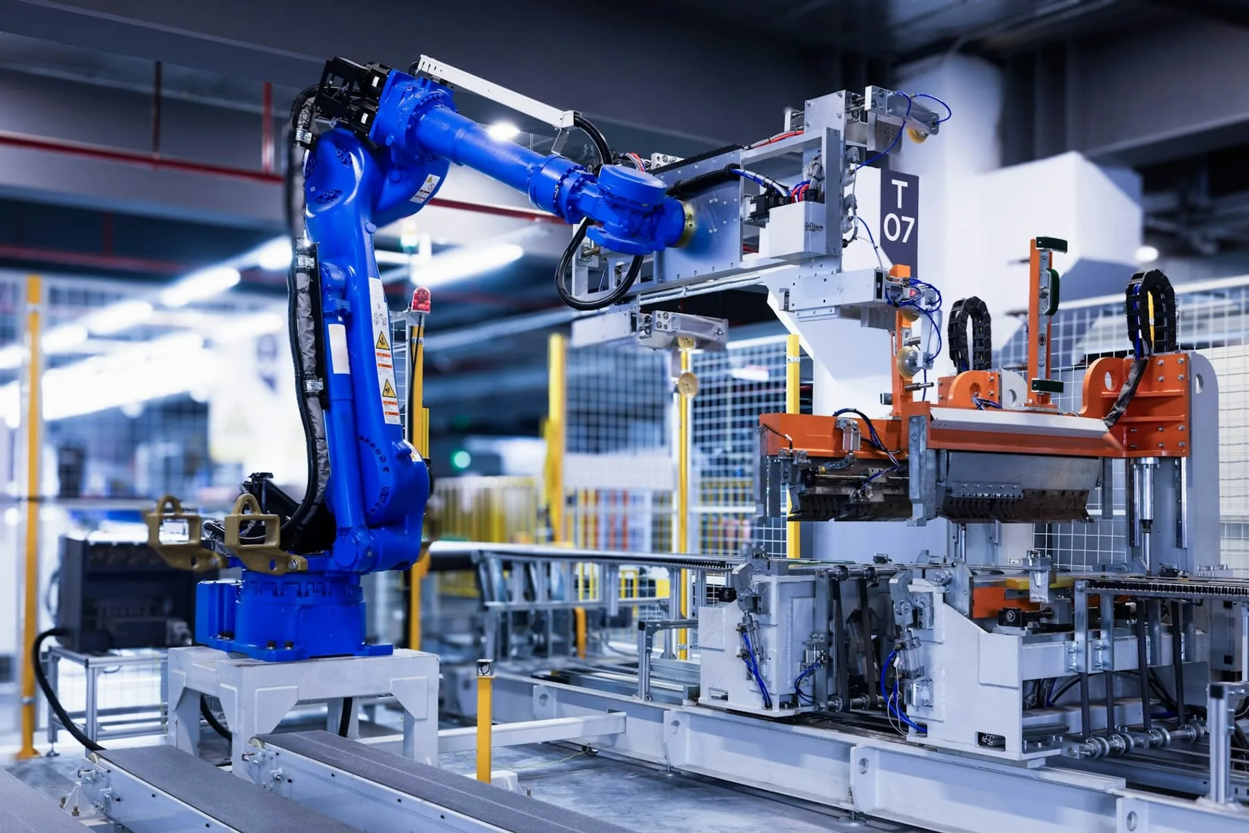 A blue industrial robot arm at an automated station in a factory