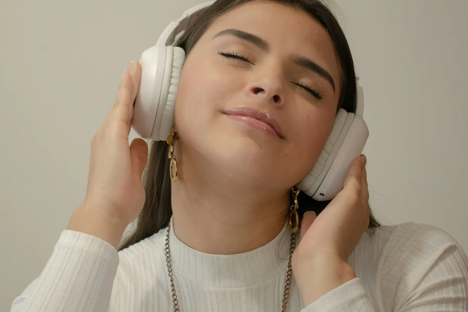A woman wearing white headphones with her eyes closed