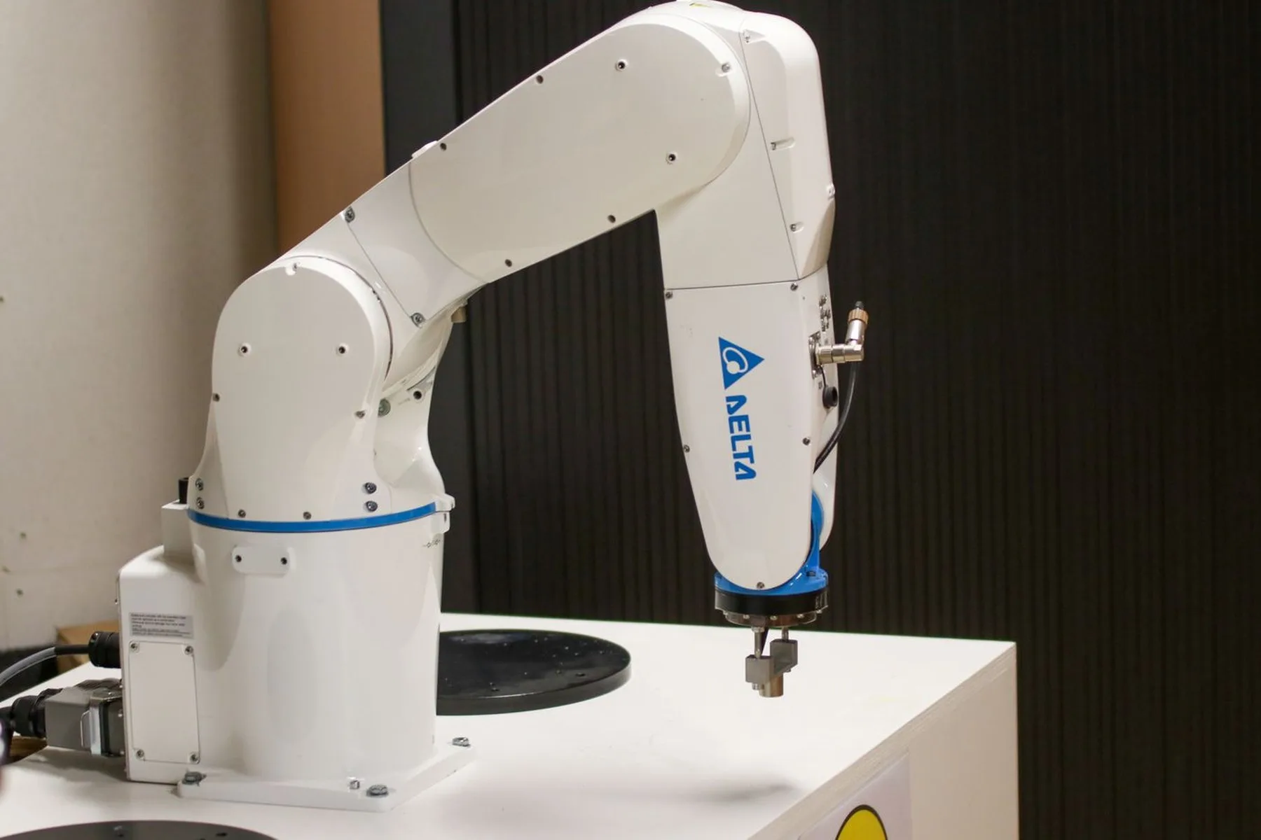 A white six-axis robot arm mounted on a laboratory bench