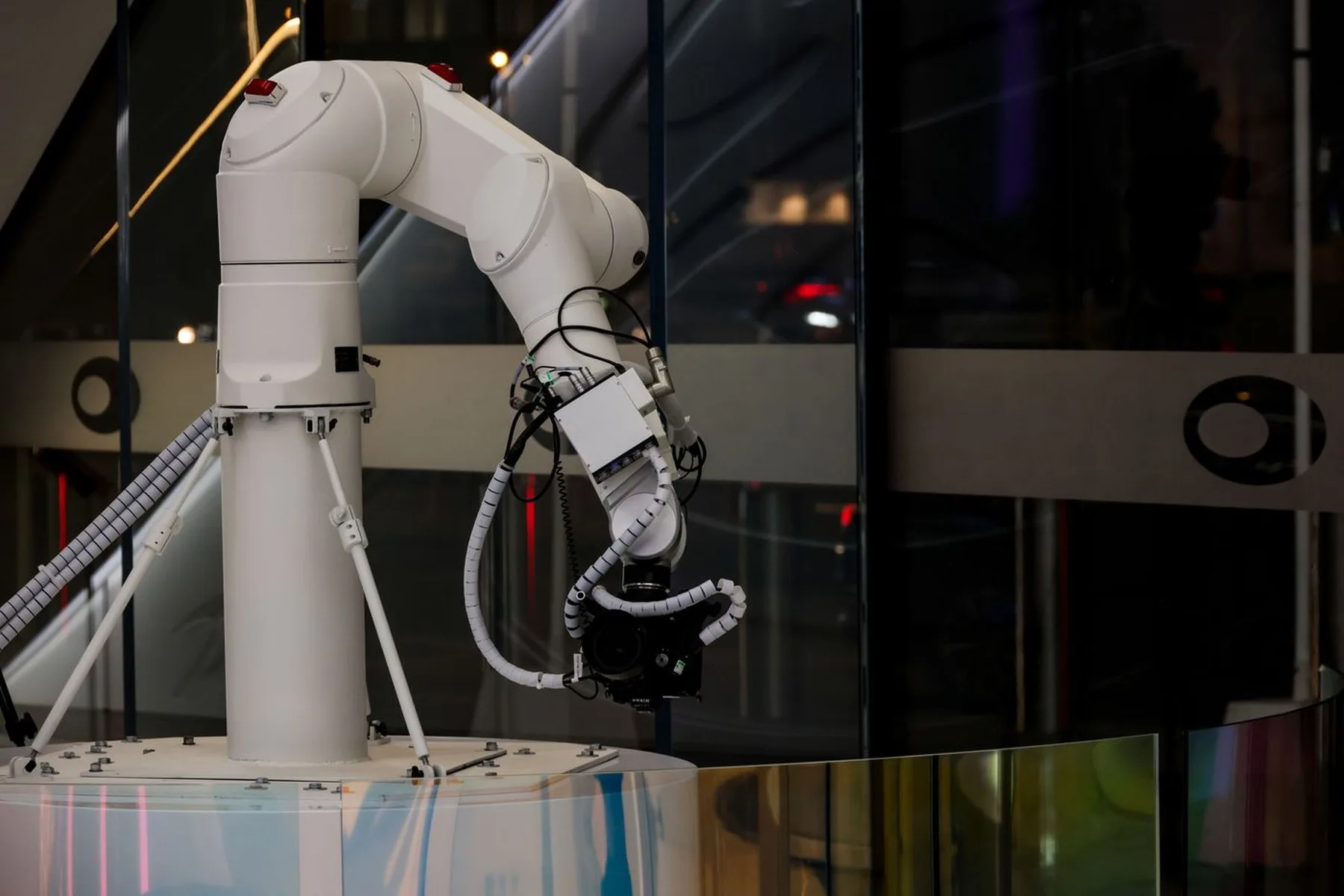 A white robot arm lit against a dark reflective background