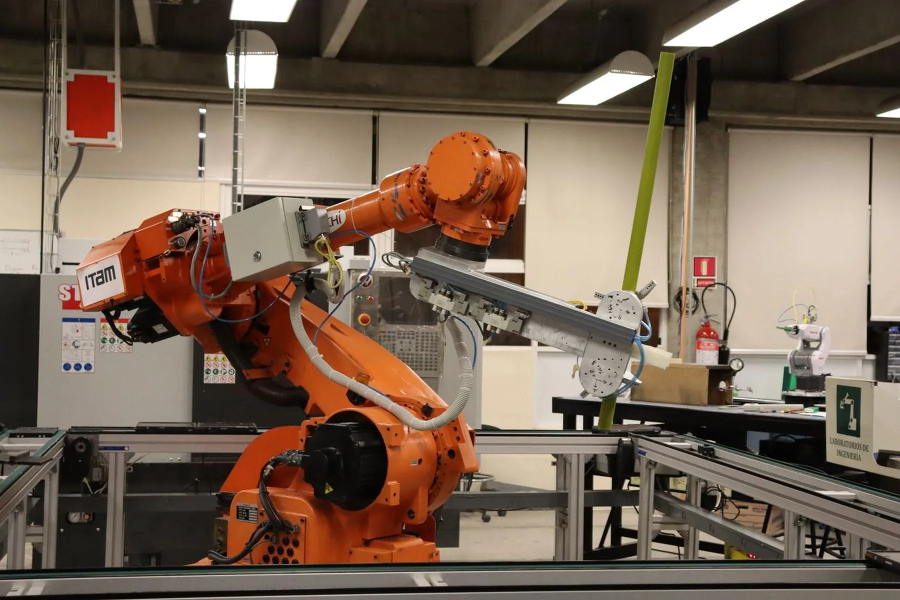 An orange industrial robot arm working on an automated production line