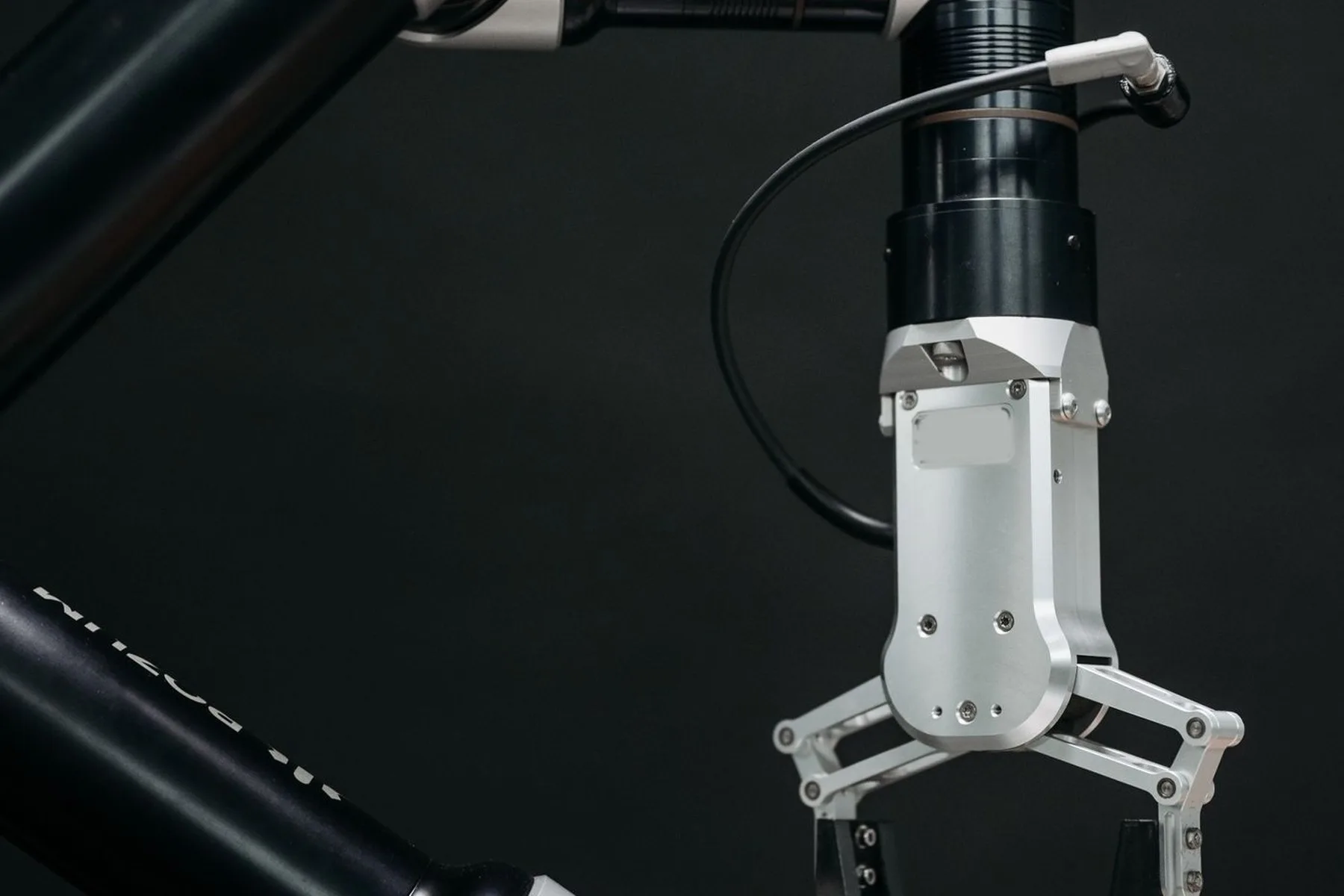A three-fingered robotic gripper photographed against a dark background